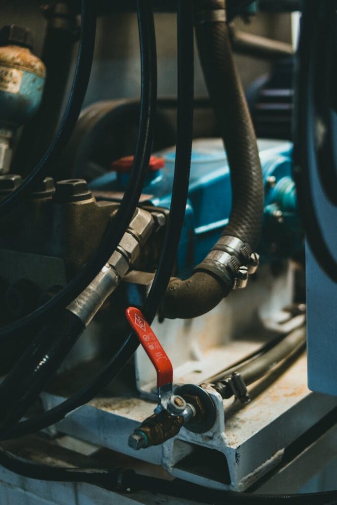 pexels-photo-10290626 Detailed view of an industrial engine showcasing hoses, levers, and painted parts.